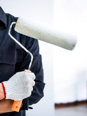 Male Painter with arm crossed holding paint roller, Interior working with paint roller in room, shape and structure.